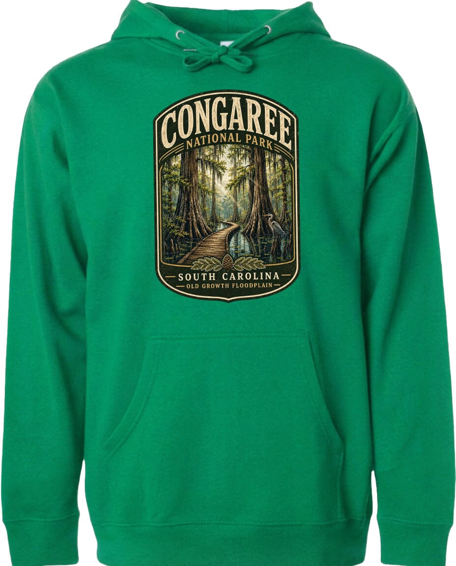 A green hoodie with a graphic design depicting a forest scene and a path leading through it, along with the text "CONGAREE NATIONAL PARK SOUTH CAROLINA".