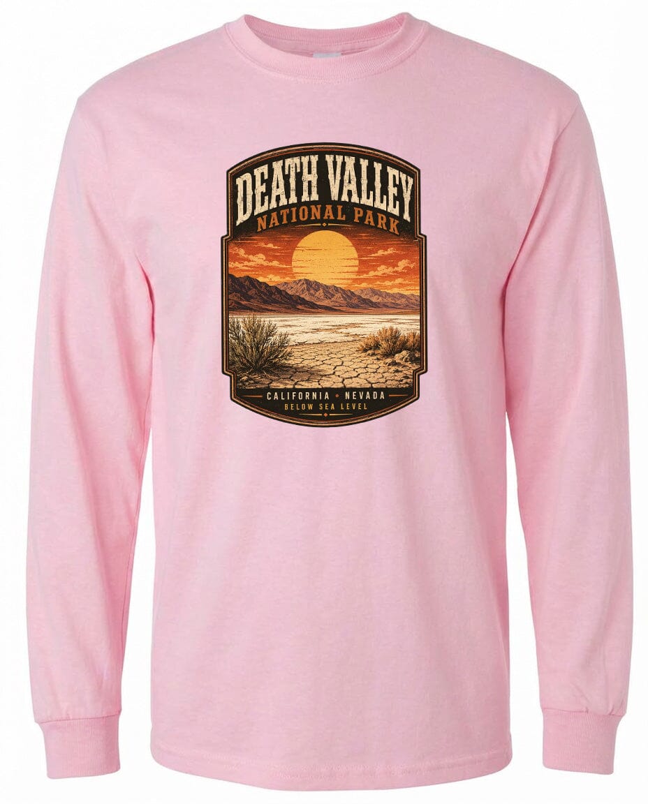 A pink long-sleeved t-shirt with a graphic design depicting a scenic landscape with mountains, a sunset, and desert vegetation.