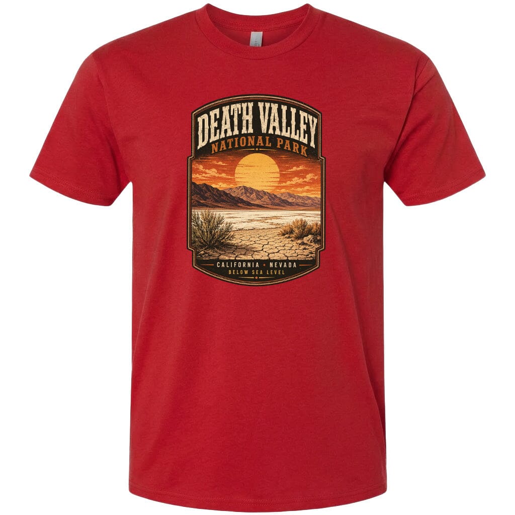 A red t-shirt with a graphic design depicting a desert landscape with mountains, a sunset, and a label that reads "DEATH VALLEY NATIONAL PARK CALIFORNIA NEVADA BELOW SEA LEVEL".