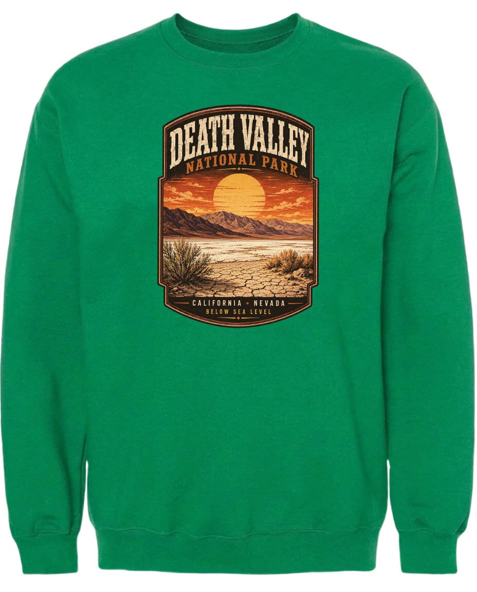 A green sweatshirt with a graphic design depicting Death Valley National Park, including a sunset, mountains, and desert landscape.