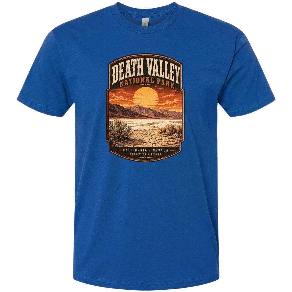 A blue t-shirt with a graphic design depicting a desert landscape with mountains, a sunset, and a desert plant.