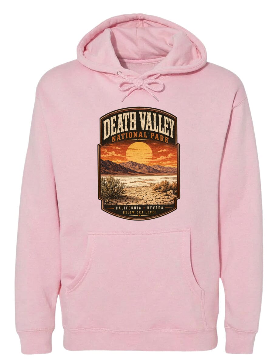 A pink hoodie with a graphic design depicting Death Valley National Park, including a sunset landscape and mountains.