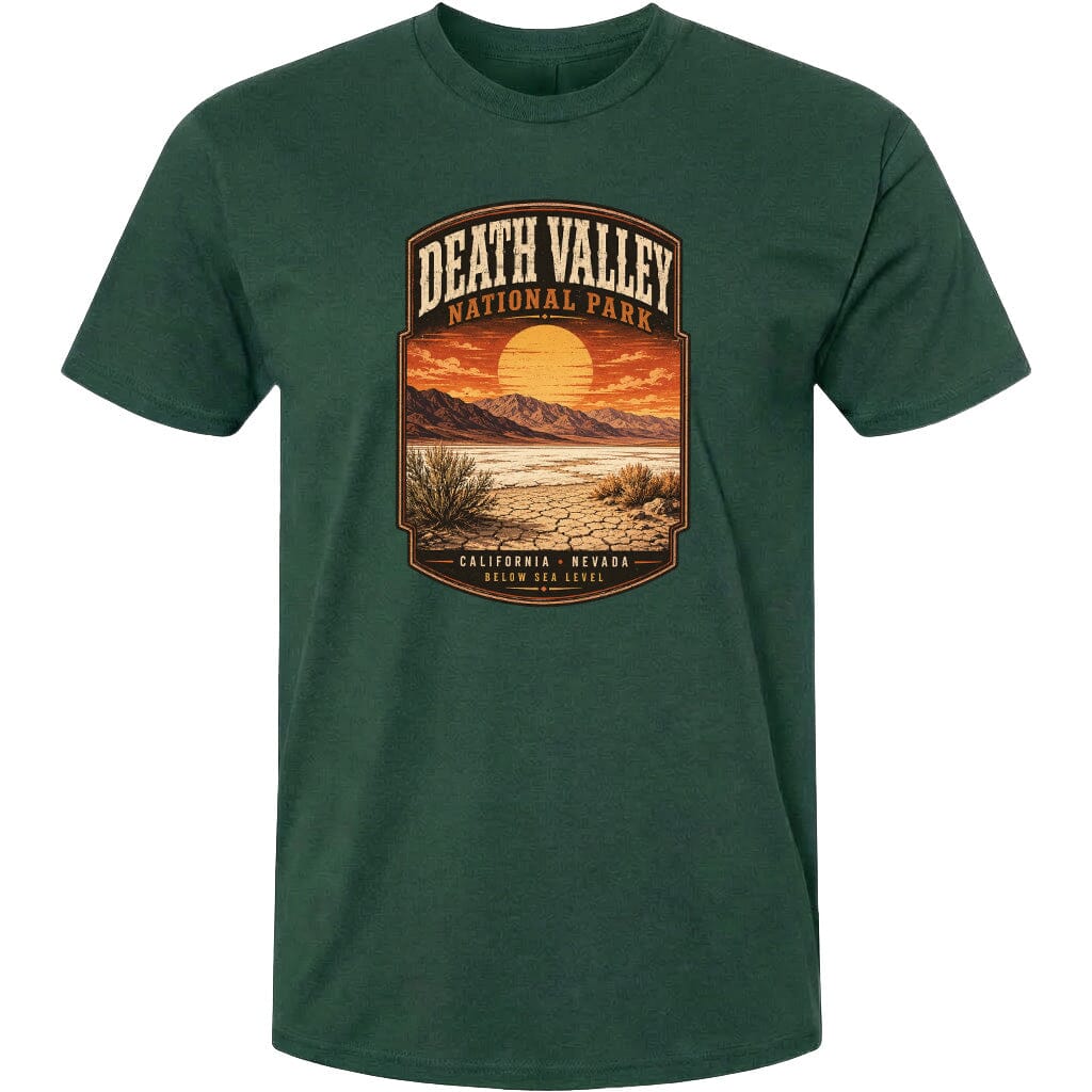 A green t-shirt with a graphic design depicting a desert landscape with mountains, a sunset, and a desert plant.