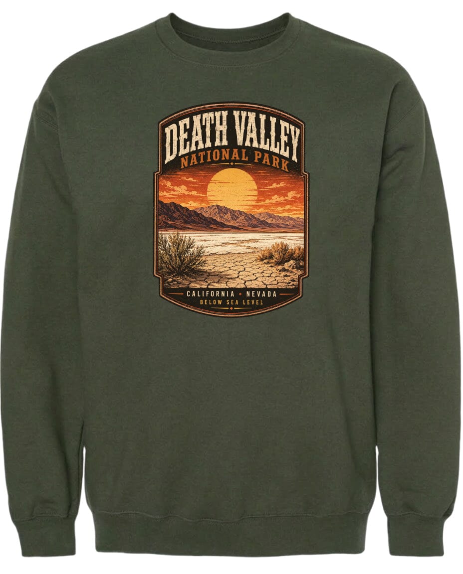 A graphic design on a dark green sweatshirt depicting a desert landscape with mountains, a sunset, and a desert plant.