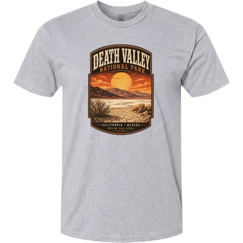 A gray t-shirt with a graphic design depicting a desert landscape with mountains, a sunset, and a desert plant.