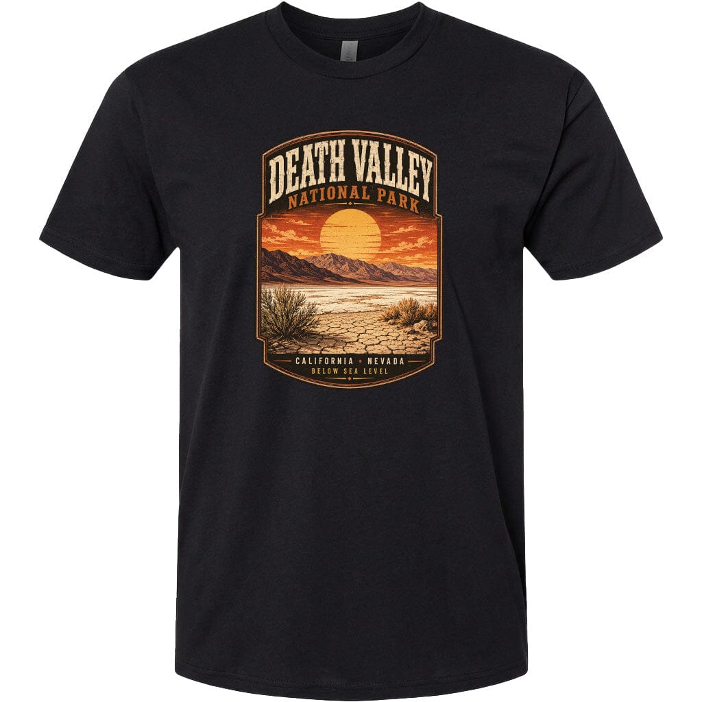 A black t-shirt with a graphic design depicting a desert landscape with mountains, a sunset, and a desert plant.
