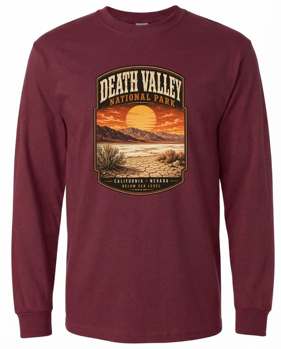 A long-sleeved burgundy t-shirt with a graphic design depicting a desert landscape with a sunset and mountains in the background.