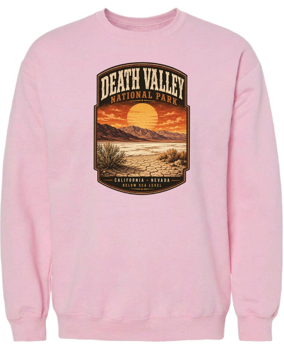 A pink sweatshirt with a graphic design depicting Death Valley National Park, including a sunset over the desert landscape.
