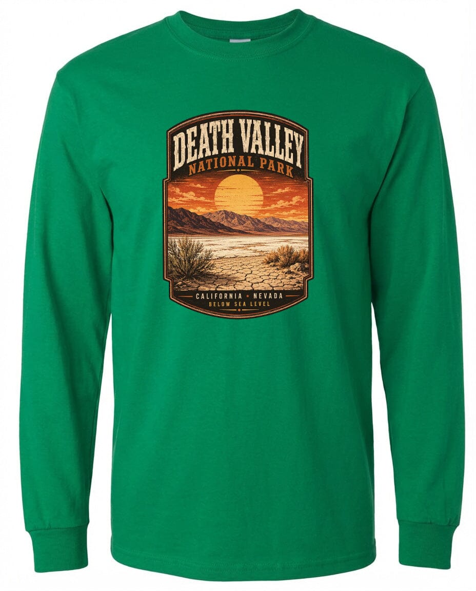 A green long-sleeved t-shirt with a graphic design depicting Death Valley National Park, including a sunset, mountains, and desert landscape.