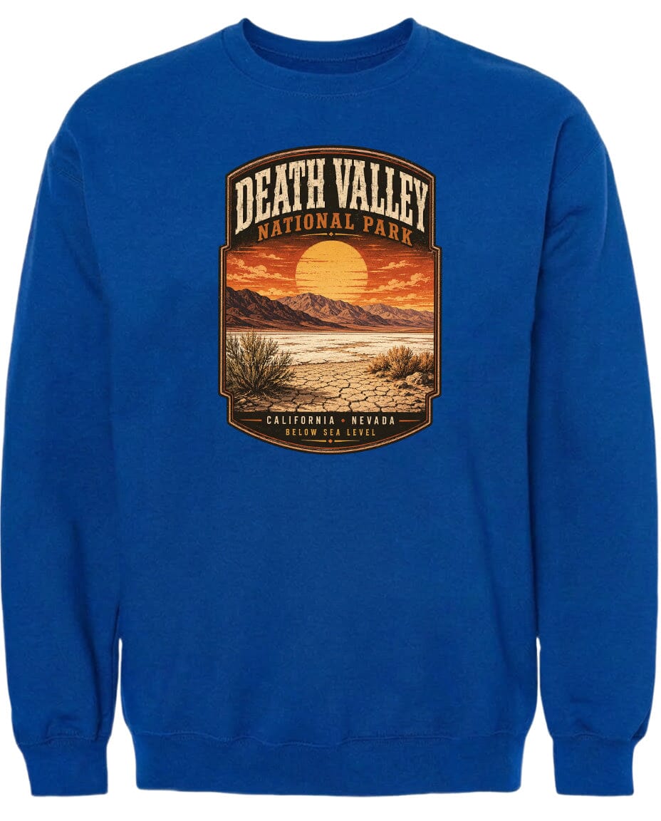 A blue sweatshirt with a graphic design depicting a desert landscape with mountains, a sunset, and a desert plant.