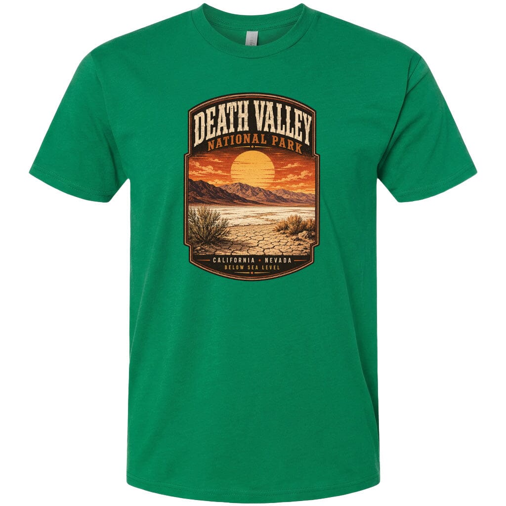 A green t-shirt with a graphic design depicting a desert landscape with mountains, a sunset, and a label that reads "DEATH VALLEY NATIONAL PARK CALIFORNIA NEVADA BELOW SEA LEVEL".
