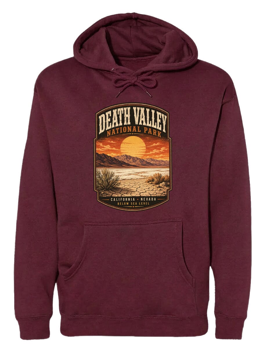 A burgundy hoodie with a graphic design depicting Death Valley National Park, including a sunset over the mountains and desert landscape.