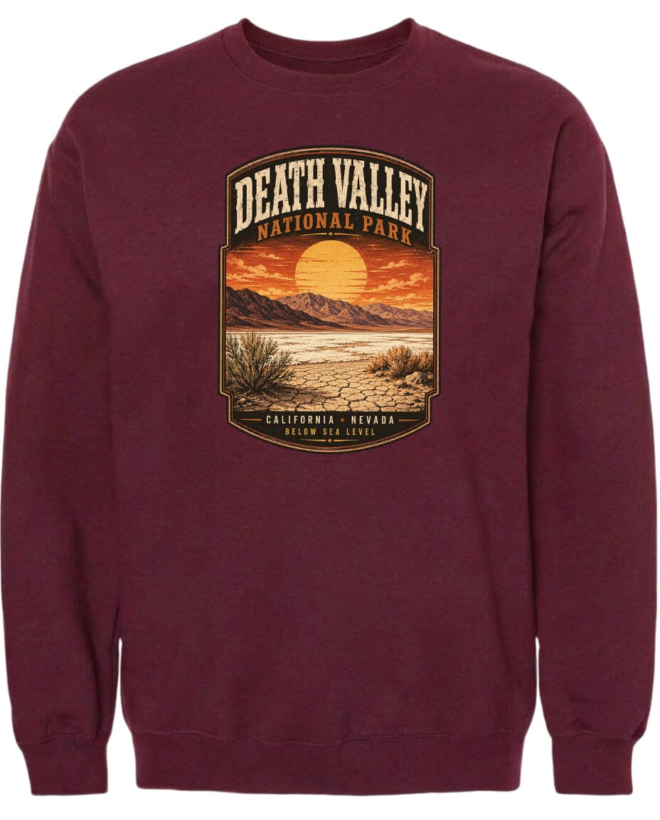 A burgundy sweatshirt with a graphic design depicting Death Valley National Park, including a sunset over the desert landscape and mountains in the background.