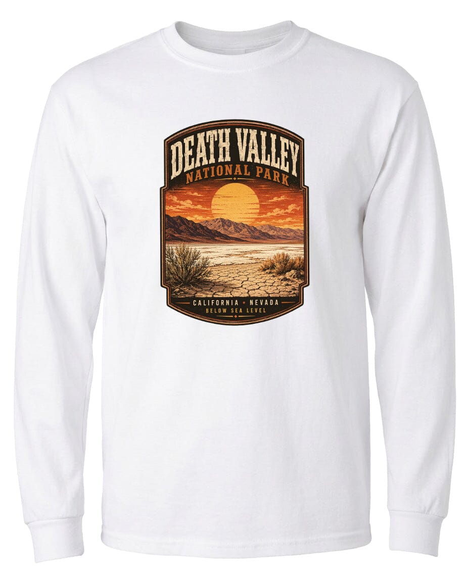 A white long-sleeved t-shirt with a graphic design depicting a desert landscape with mountains, a sunset, and a cactus plant.