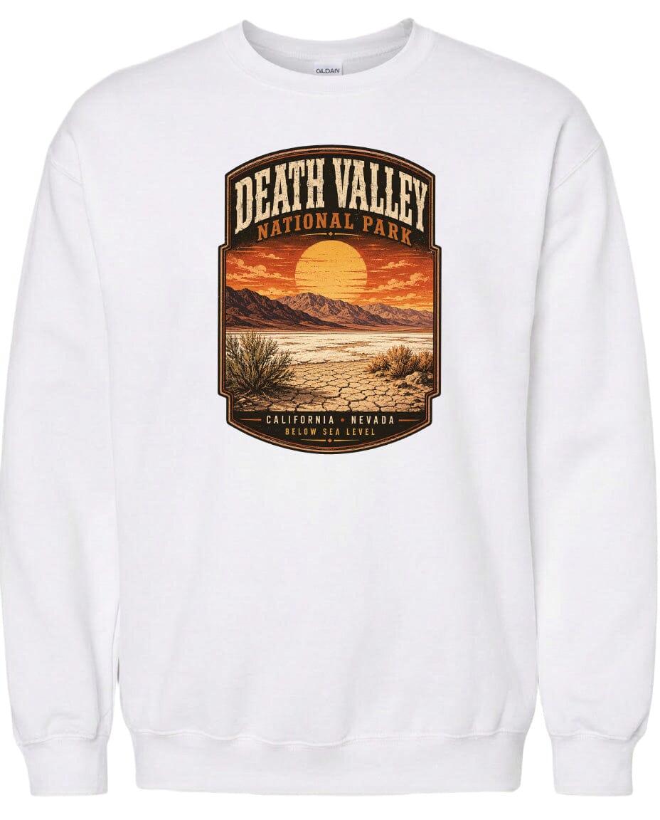A white sweatshirt with a graphic design depicting a desert landscape with mountains, a sunset, and a desert plant.