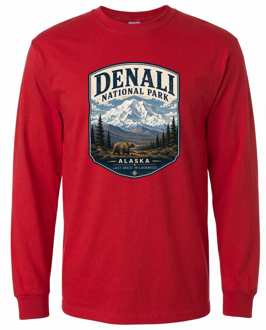 A red long-sleeved t-shirt with a graphic design depicting a mountain landscape with a bear in the foreground, surrounded by pine trees.