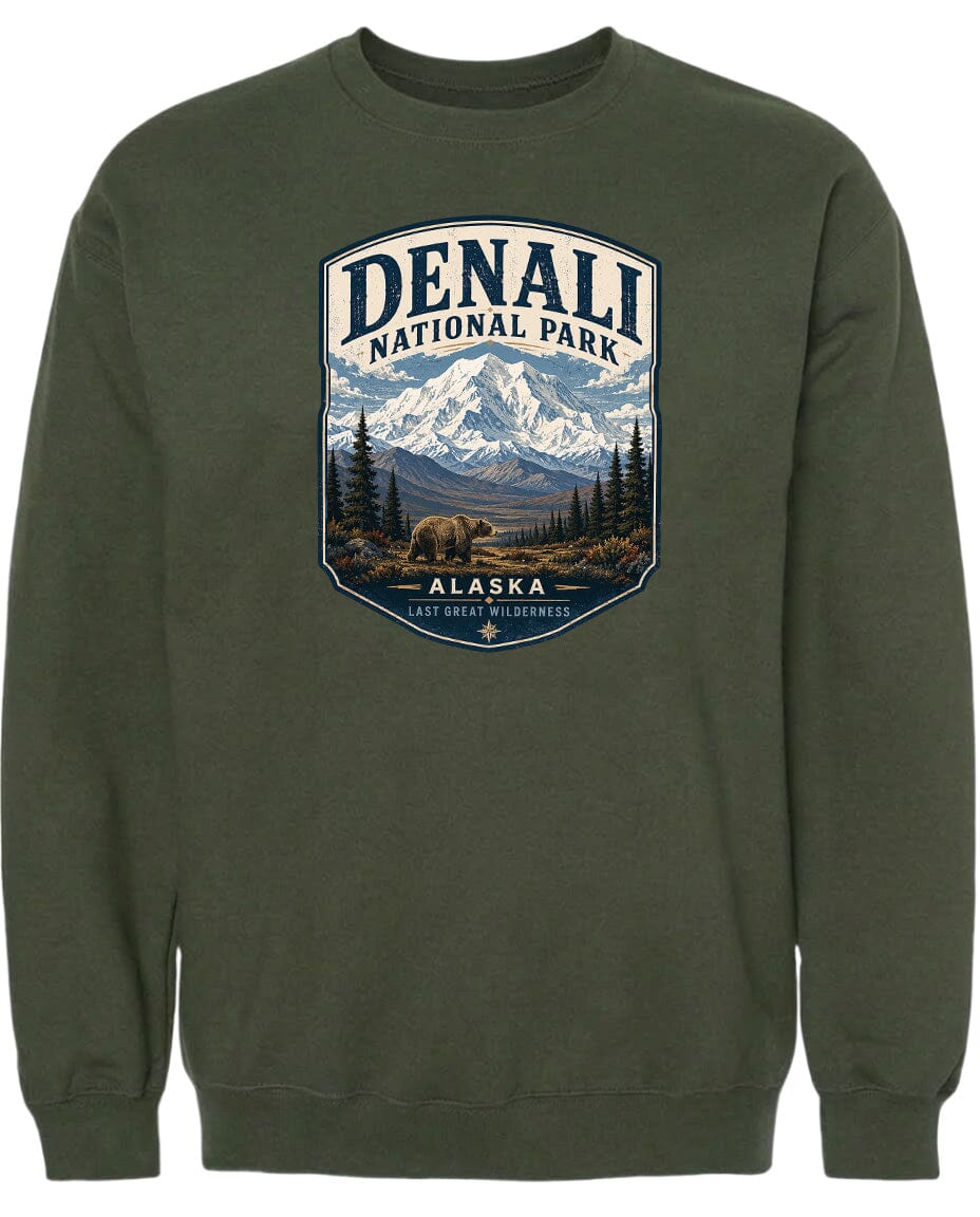 A green sweatshirt with a graphic design depicting a mountain landscape with a bear in the foreground, surrounded by pine trees and mountains.