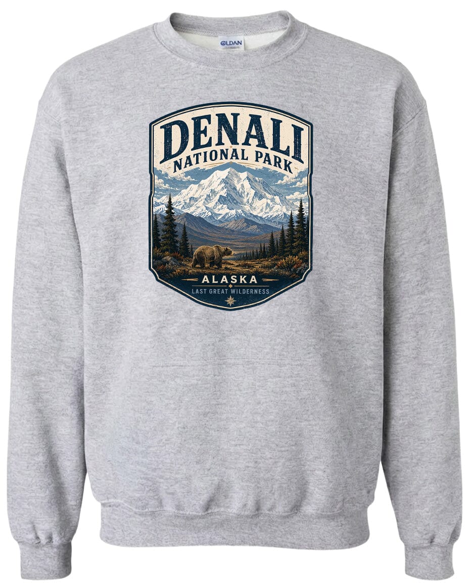 A gray sweatshirt with a graphic design depicting a mountain landscape with a bear in the foreground, surrounded by pine trees and mountains.