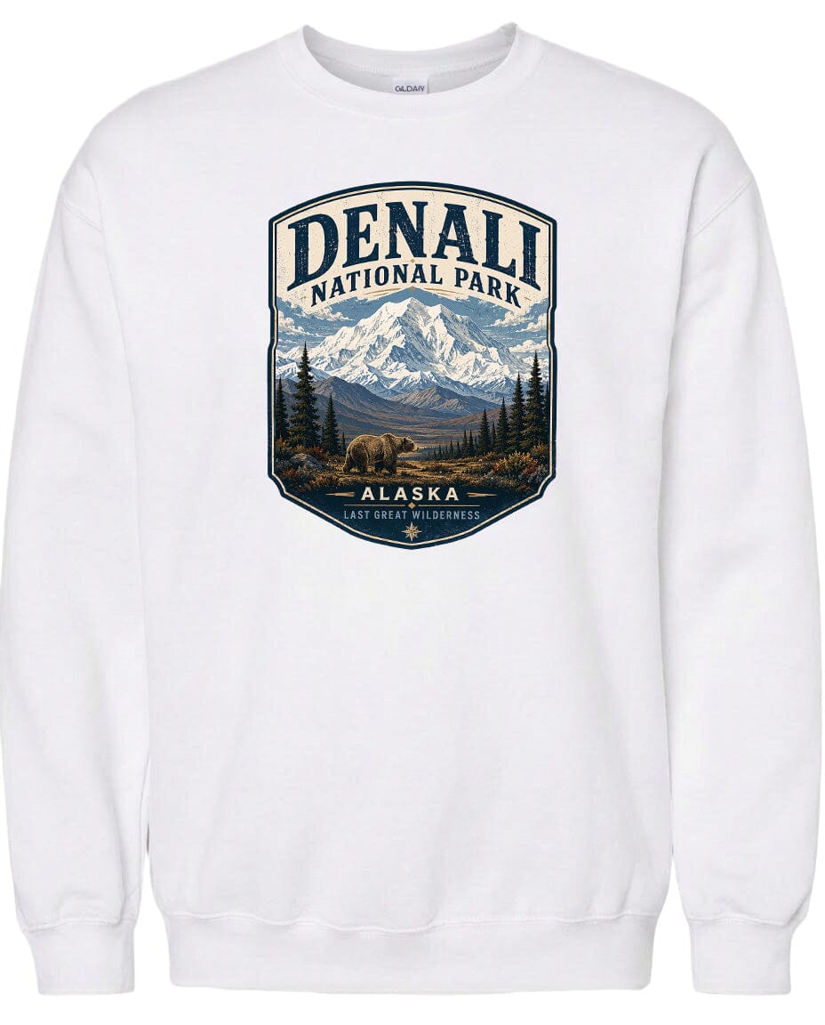 A white sweatshirt with a graphic design depicting a mountain landscape with a bear in the foreground, surrounded by pine trees and mountains.