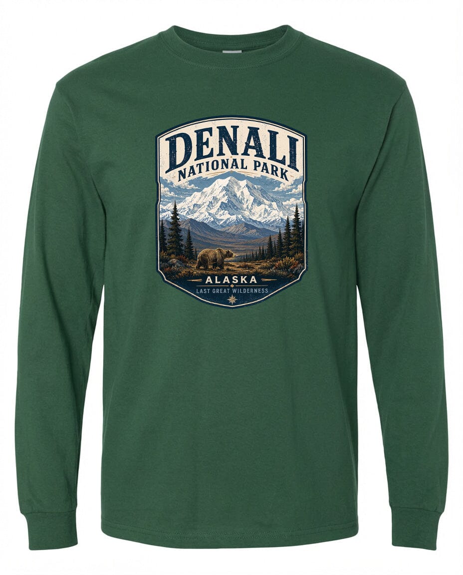 A green long-sleeved t-shirt with a graphic design depicting a mountain landscape with a bear in the foreground, surrounded by pine trees and mountains.