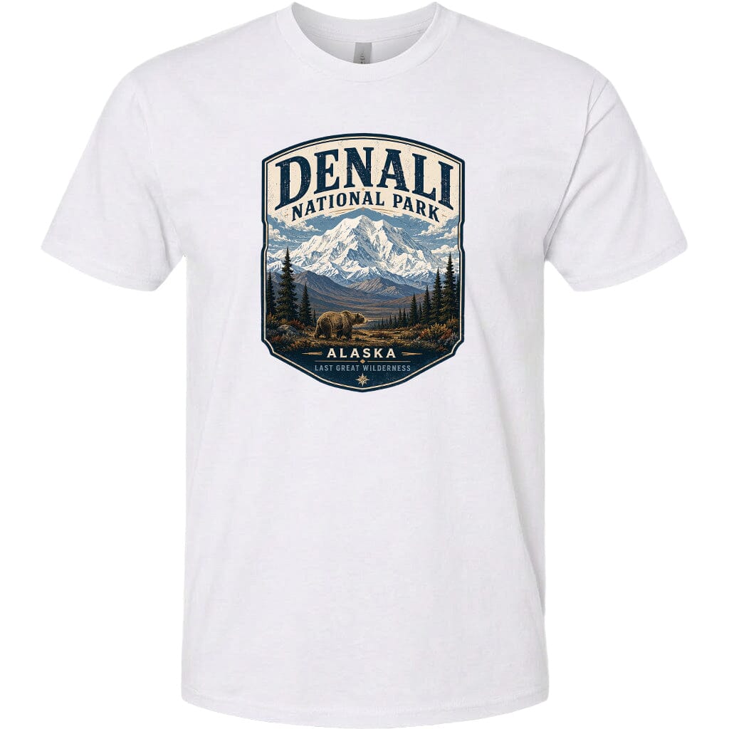 A white t-shirt with a graphic design depicting a mountain landscape with a bear in the foreground, surrounded by pine trees and mountains.