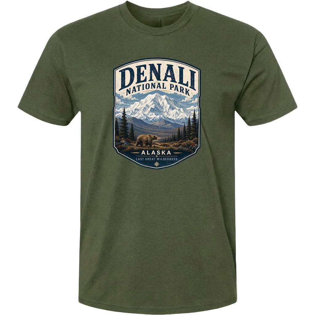 A green t-shirt with a graphic design depicting a mountain landscape with a bear in the foreground, surrounded by pine trees and mountains.