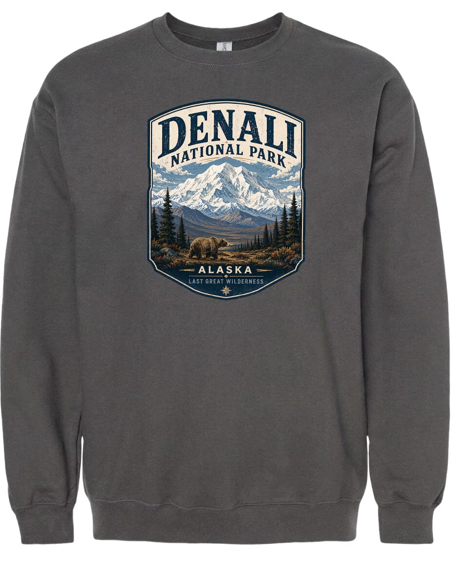 A gray sweatshirt with a graphic design depicting a mountain landscape with a bear in the foreground, surrounded by pine trees and mountains.