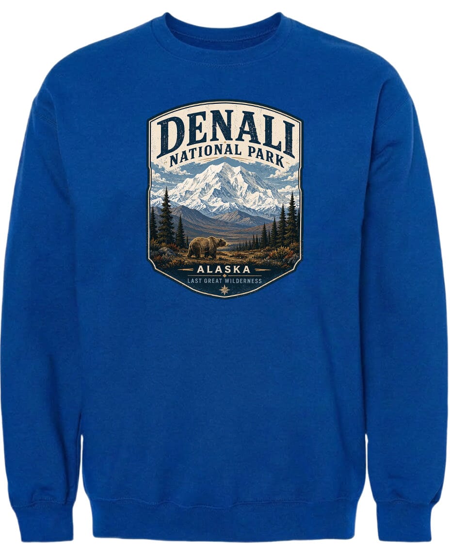 A blue sweatshirt with a graphic design depicting a mountain landscape with a bear in the foreground, surrounded by pine trees and mountains.