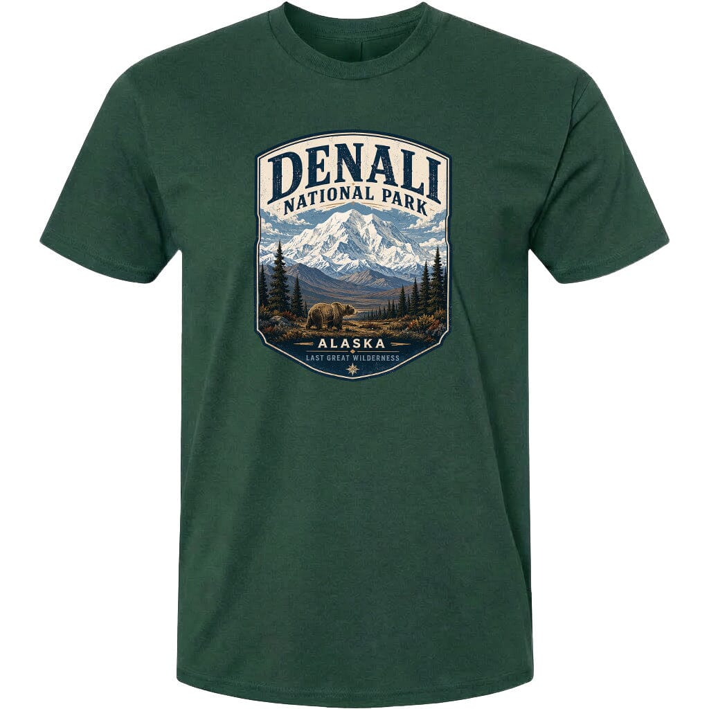 A green t-shirt with a graphic design depicting a mountain landscape with a bear in the foreground, surrounded by pine trees and mountains.