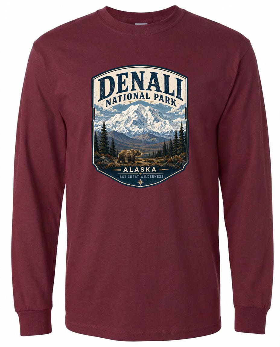 A long-sleeved burgundy t-shirt with a graphic design featuring a mountain landscape with a bear in the foreground, surrounded by pine trees.
