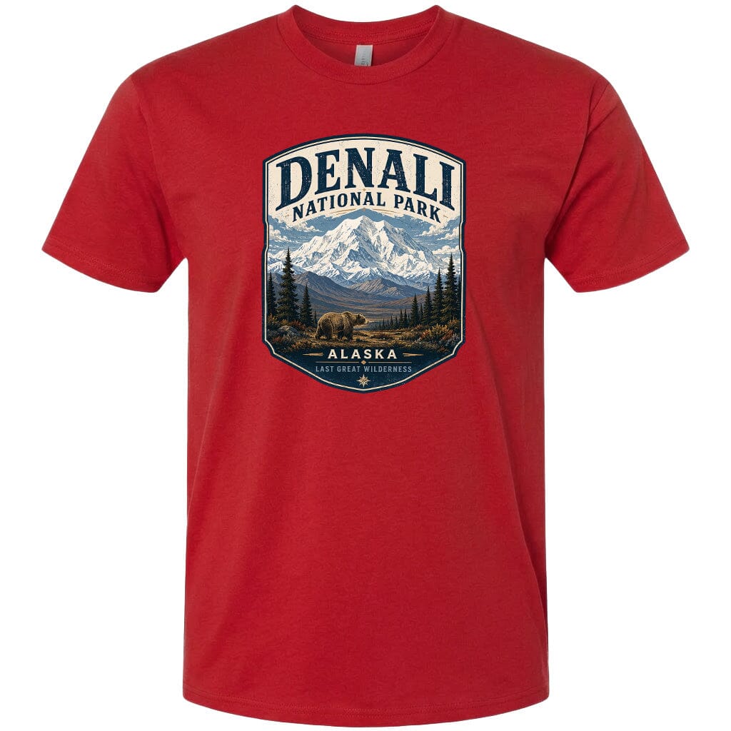 A red t-shirt with a graphic design depicting a mountain landscape with a bear in the foreground, surrounded by pine trees and mountains.