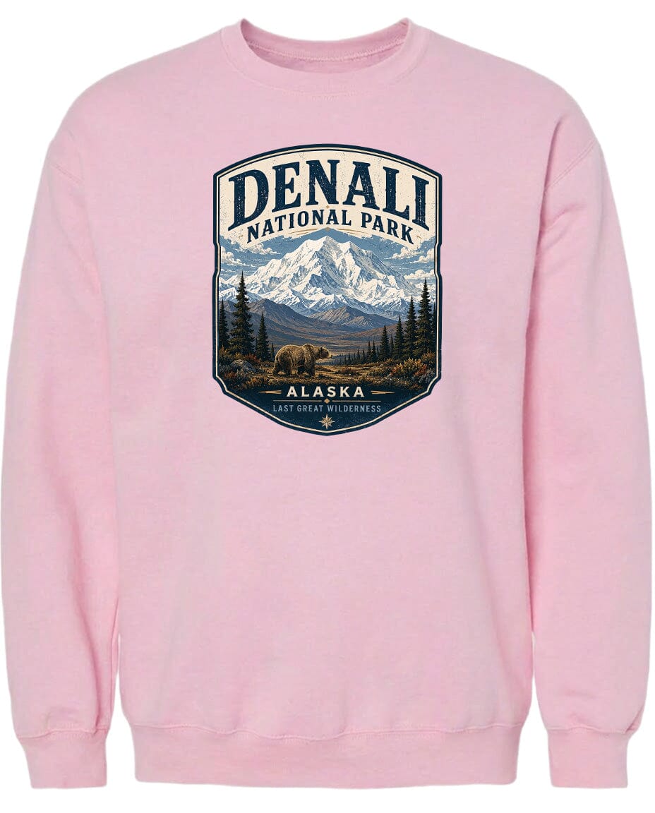 A pink sweatshirt with a graphic design depicting Denali National Park in Alaska, featuring a mountain landscape with a bear in the foreground.