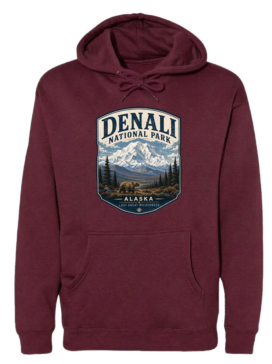 A burgundy hoodie with a graphic design depicting Denali National Park in Alaska, featuring a mountain landscape with a bear in the foreground.