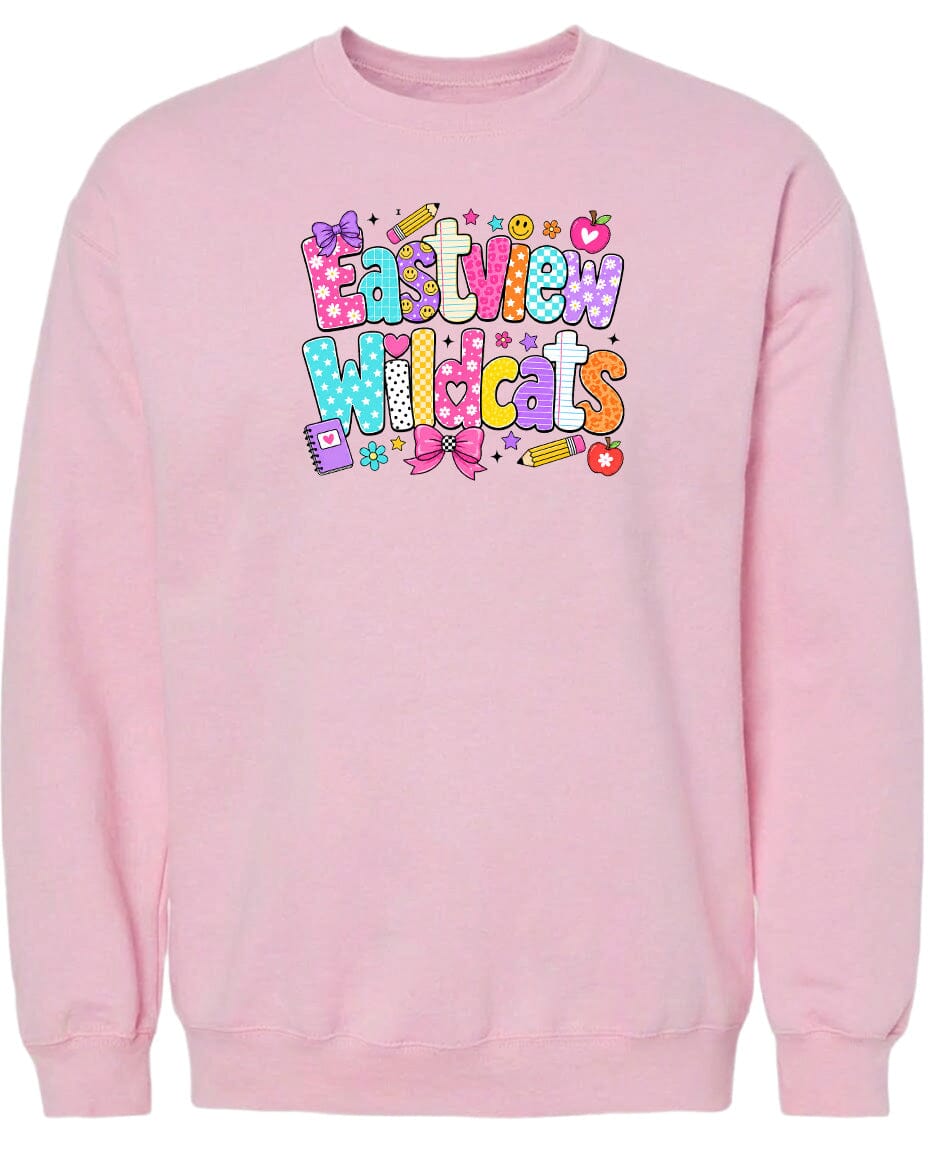 A pink sweatshirt with a colorful graphic design featuring the text "Eastview Wildcats" and various decorative elements such as stars, hearts, and a pencil.