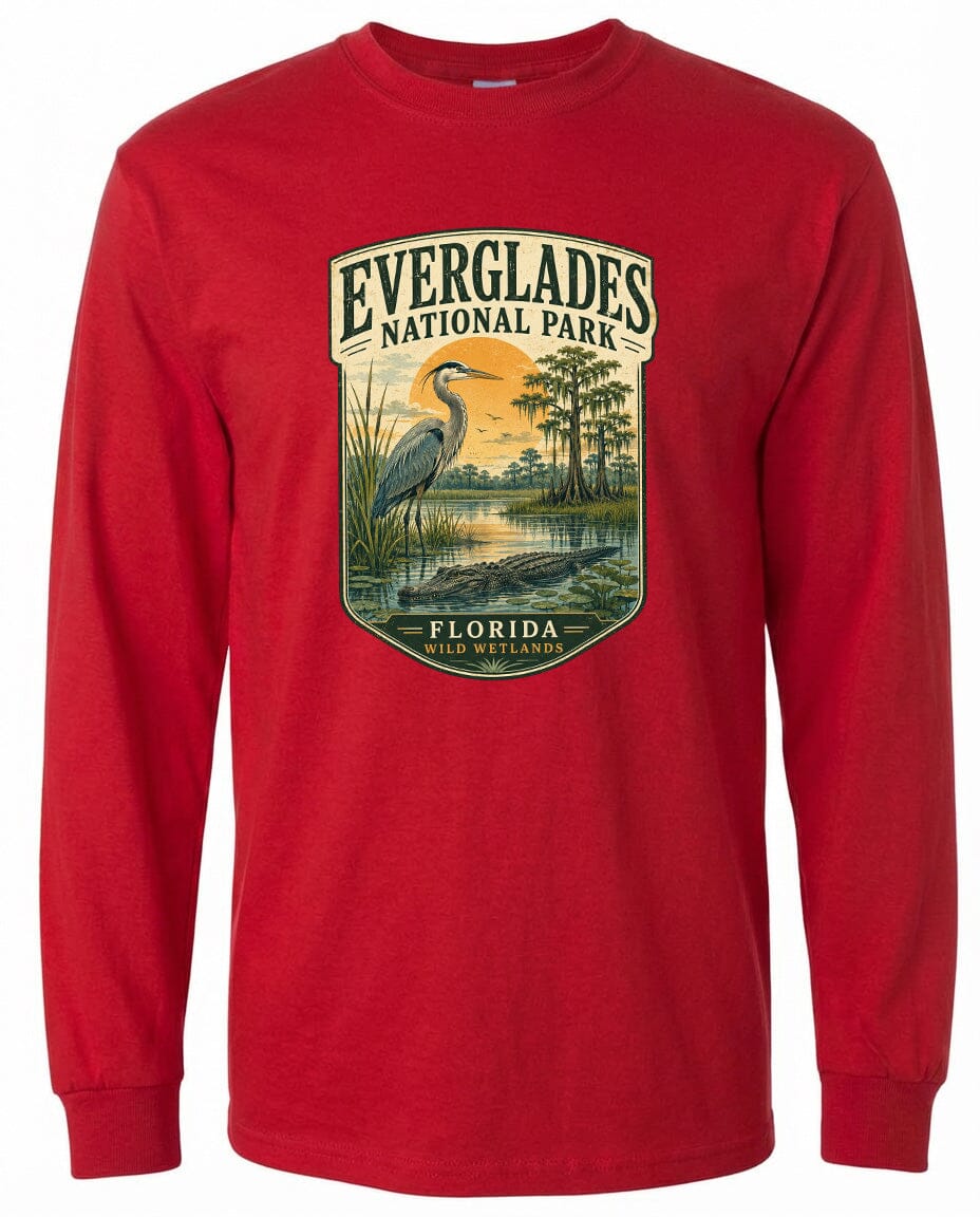 A red long-sleeved t-shirt with a graphic design depicting a bird standing in a marshy area with a lake and trees in the background.