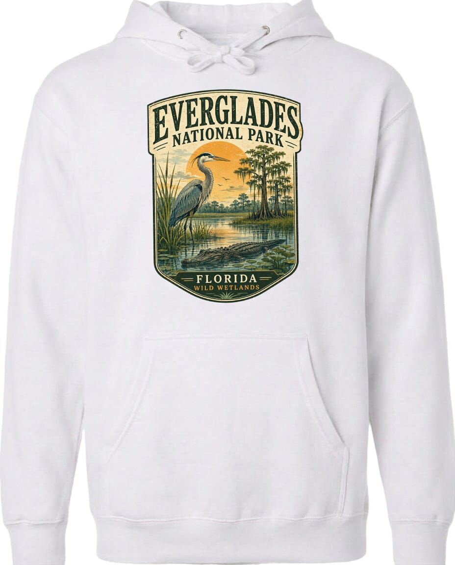 A white hoodie with a graphic design depicting a bird standing in a marshy area with trees and a sunset in the background.