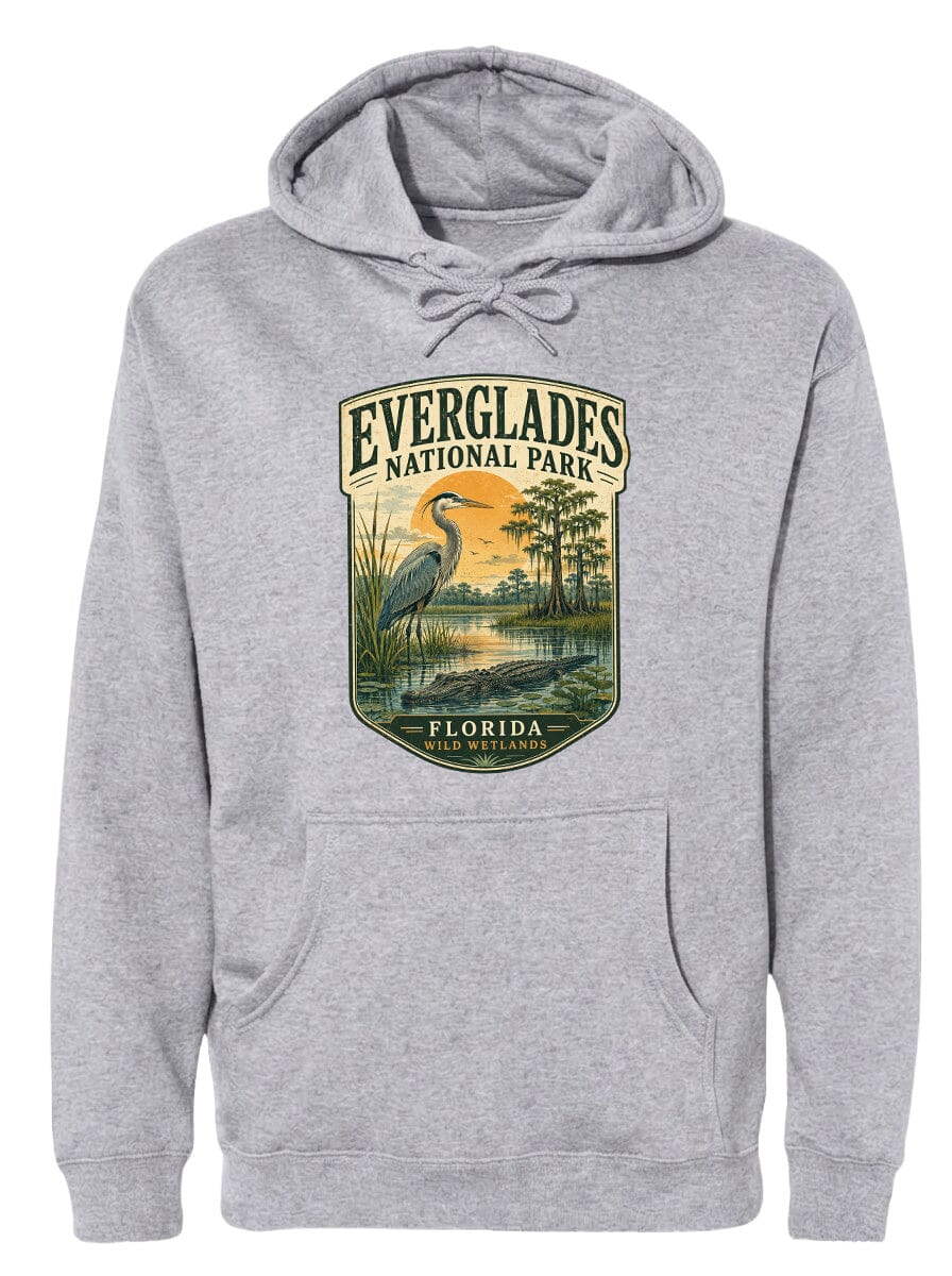 A gray hoodie with a graphic design depicting a bird, likely a heron, standing in a marshy area with a sunset in the background.