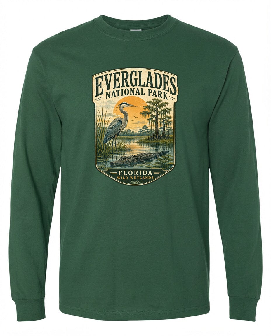 A green long-sleeved t-shirt with a graphic design depicting a bird, a pond, and trees, along with the text "EVERGLADES NATIONAL PARK FLORIDA WILD WETLANDS".