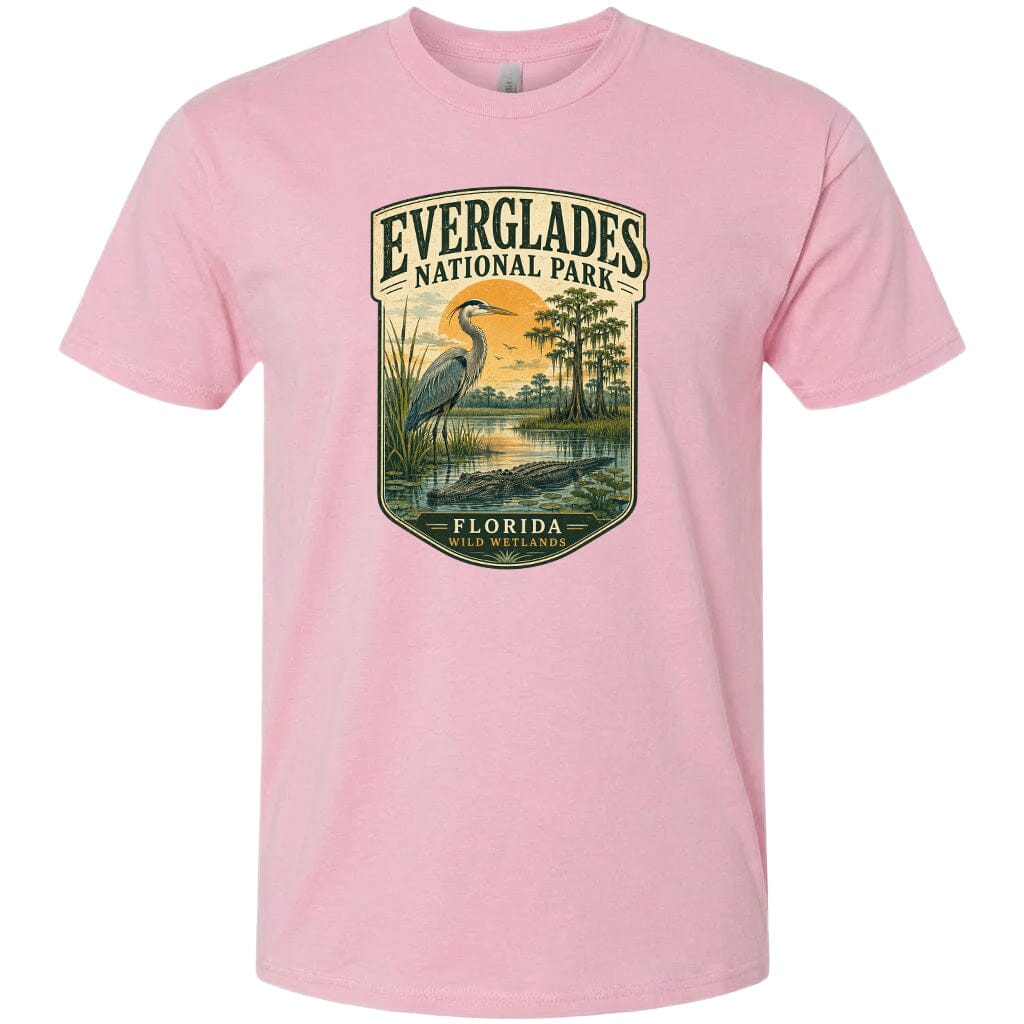 A pink t-shirt with a graphic design depicting a bird, a water feature, and a landscape with trees and a body of water.