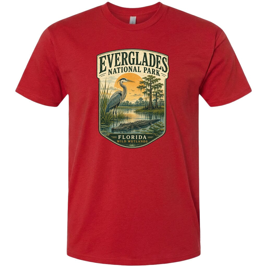 A red t-shirt with a graphic design depicting a bird, a pond, and trees, along with the text "EVERGLADES NATIONAL PARK FLORIDA WILD WETLANDS".