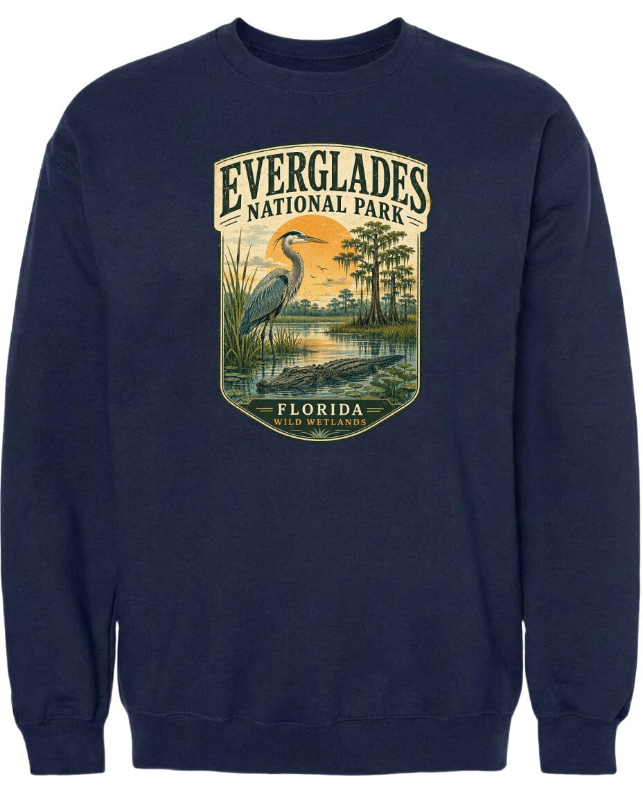 A navy blue sweatshirt with a graphic design depicting a bird, likely a heron, standing in a marshy area with trees and a sunset in the background.
