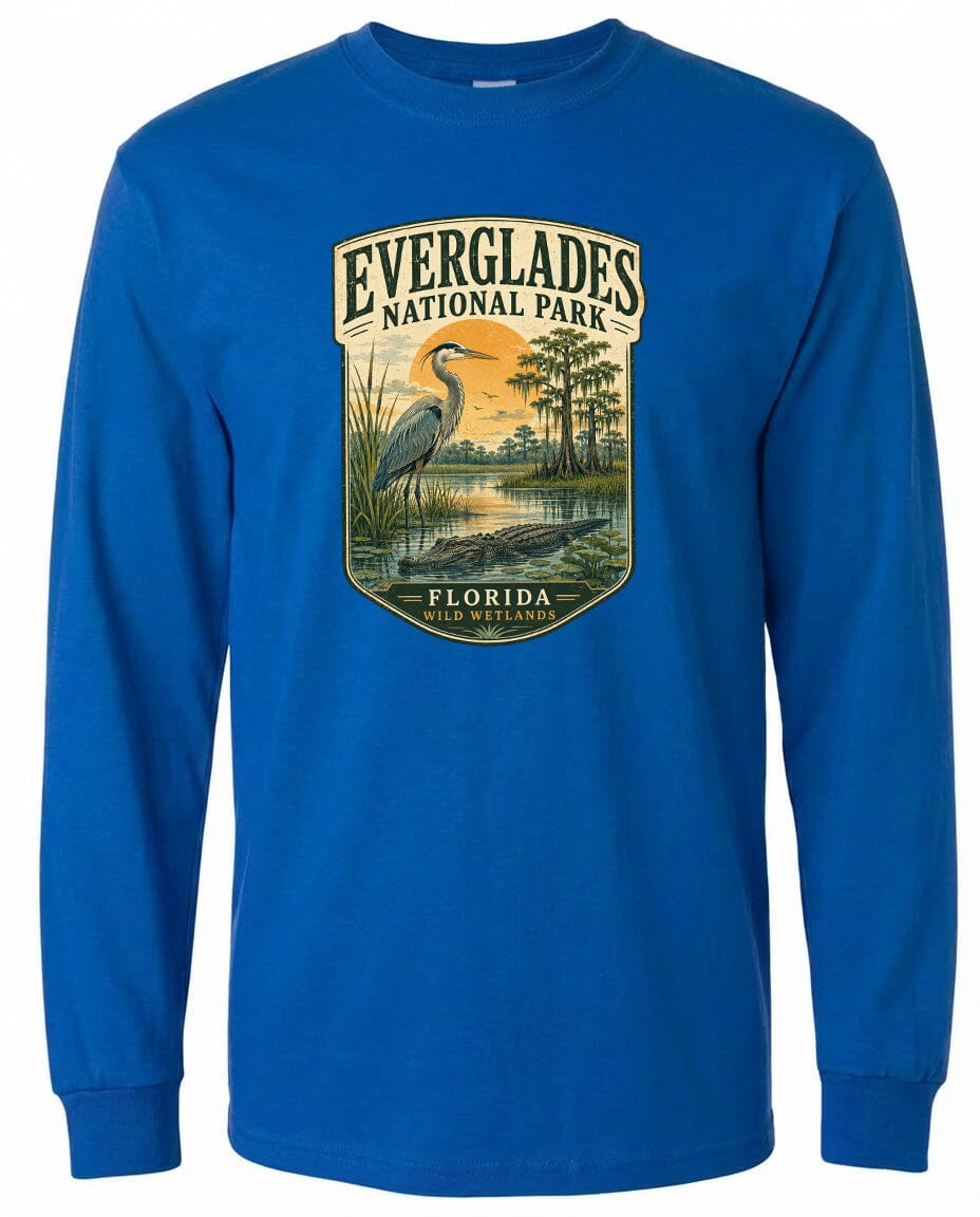 A blue long-sleeved t-shirt with a graphic design depicting a bird standing in a pond surrounded by trees and a sunset.