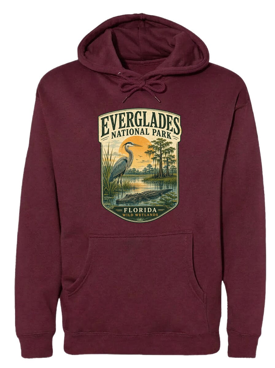 A burgundy hoodie with a graphic design depicting a bird, likely a heron, standing in a marshy area with trees and a sunset in the background.