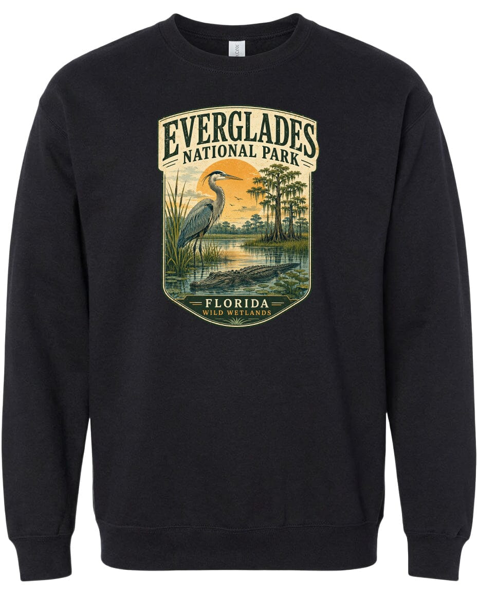 A black sweatshirt with a graphic design depicting a bird, likely a heron, standing in a marshy area with trees and a sunset in the background.
