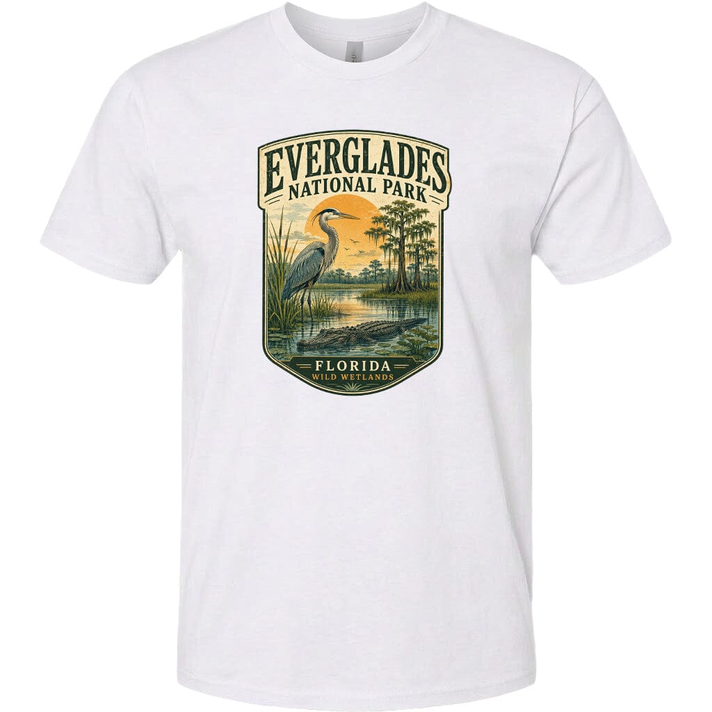 A white t-shirt with a graphic design depicting a seagull standing on a grassy area with a body of water and trees in the background, along with the text "EVERGLADES NATIONAL PARK FLORIDA WILD WESTLANDS".