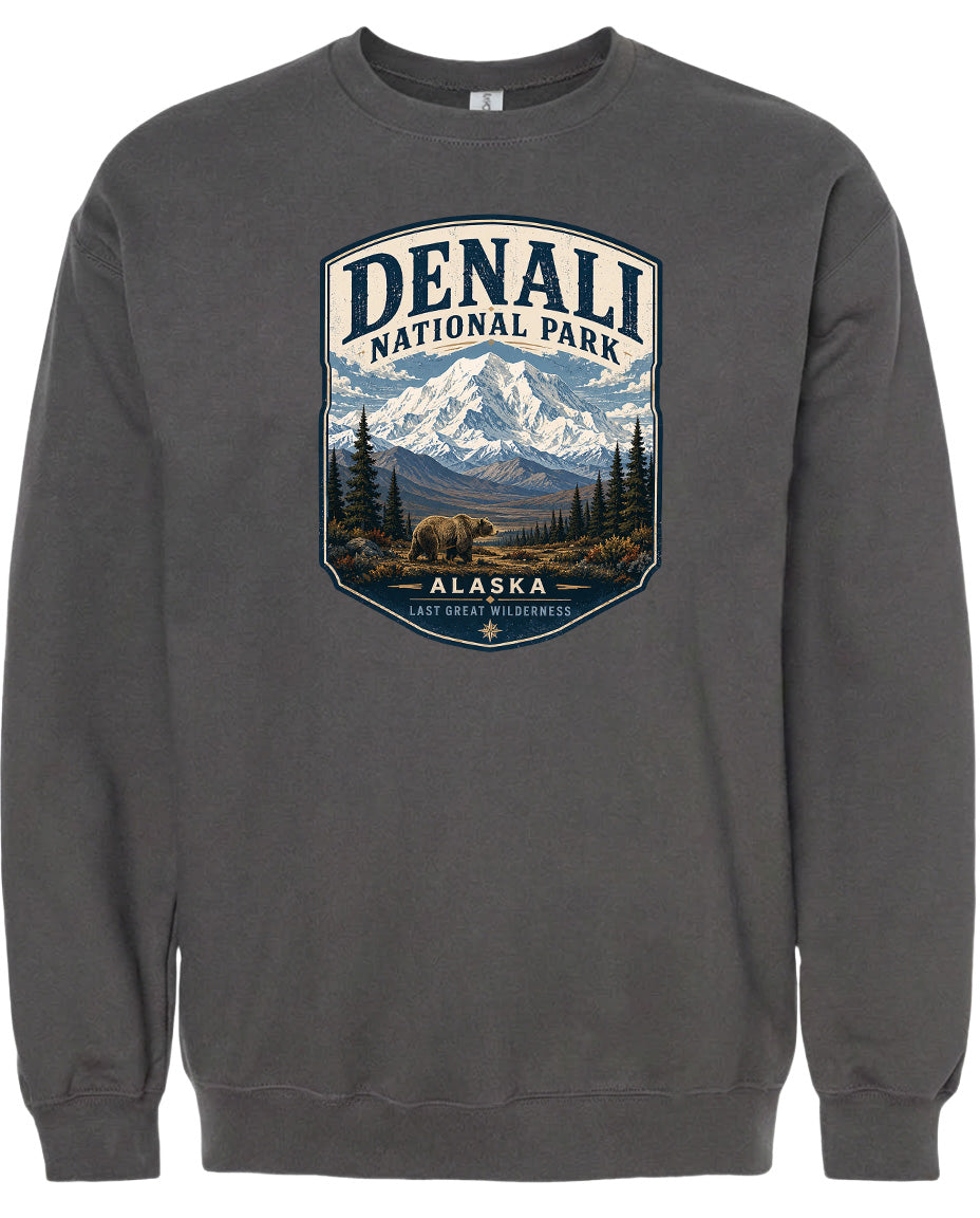 A gray sweatshirt with a graphic design depicting a mountain landscape with a bear in the foreground, surrounded by pine trees and mountains.