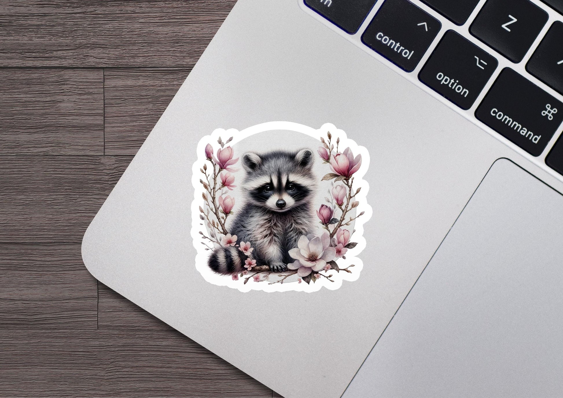 a sticker of a raccoon sitting on top of a laptop