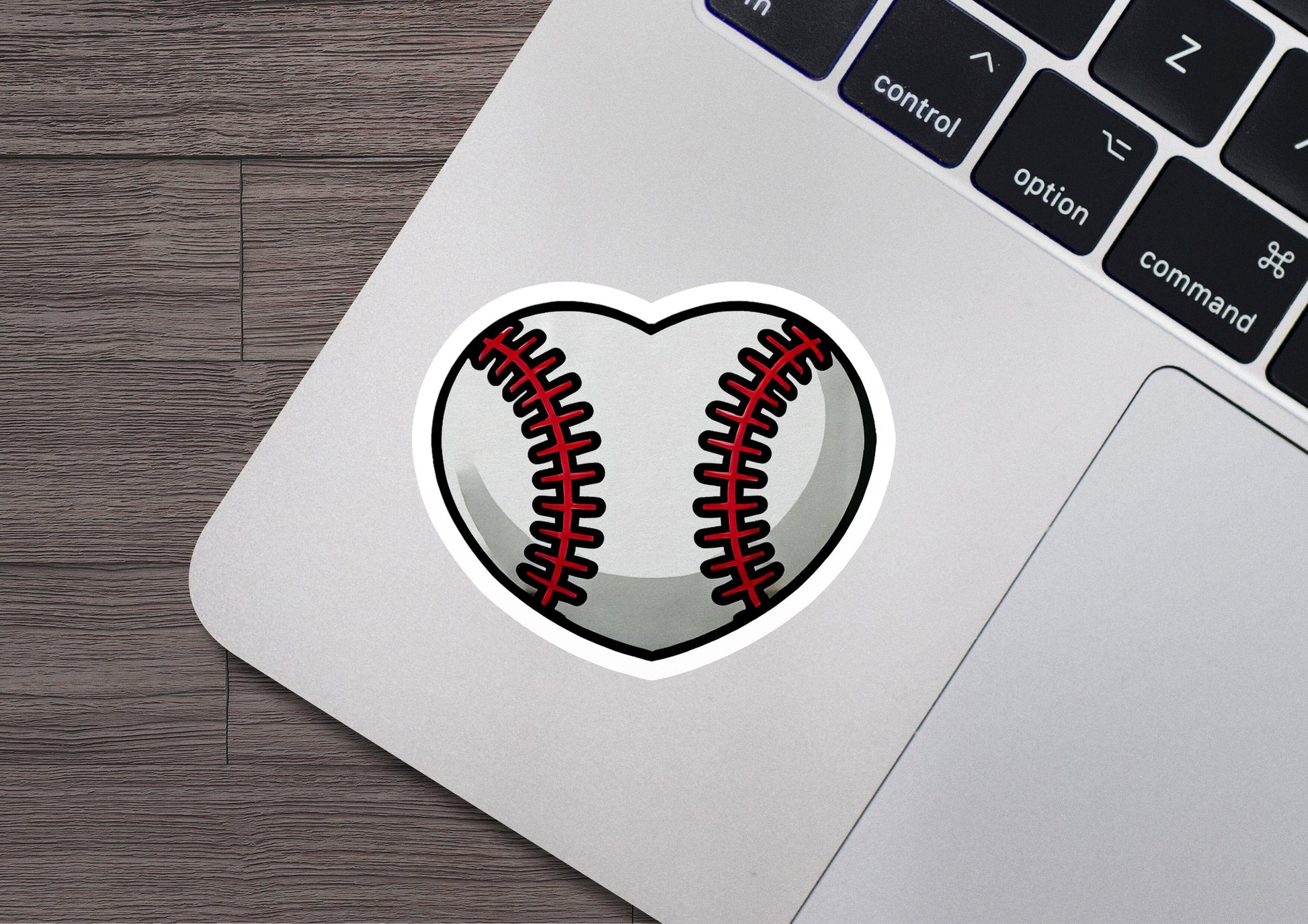 a heart shaped baseball sticker sitting on top of a laptop