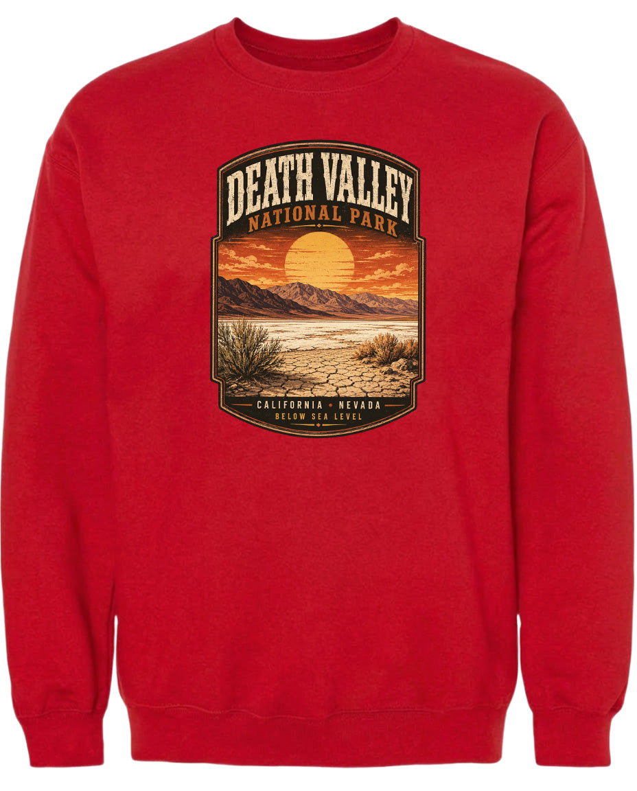 A red sweatshirt with a graphic design depicting a desert landscape with mountains, a sunset, and a desert plant.