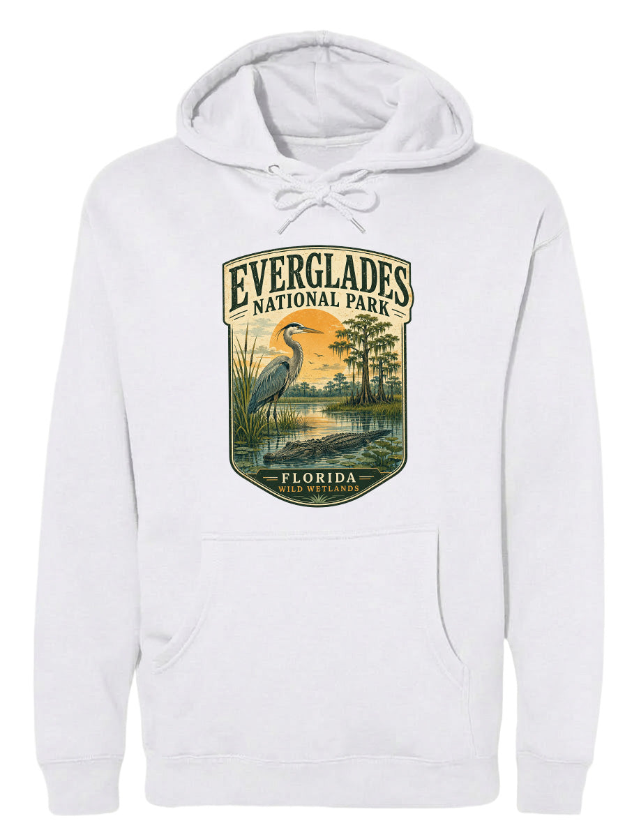 A white hoodie with a graphic design depicting a bird, likely a heron, standing in a marshy area with trees and a sunset in the background.